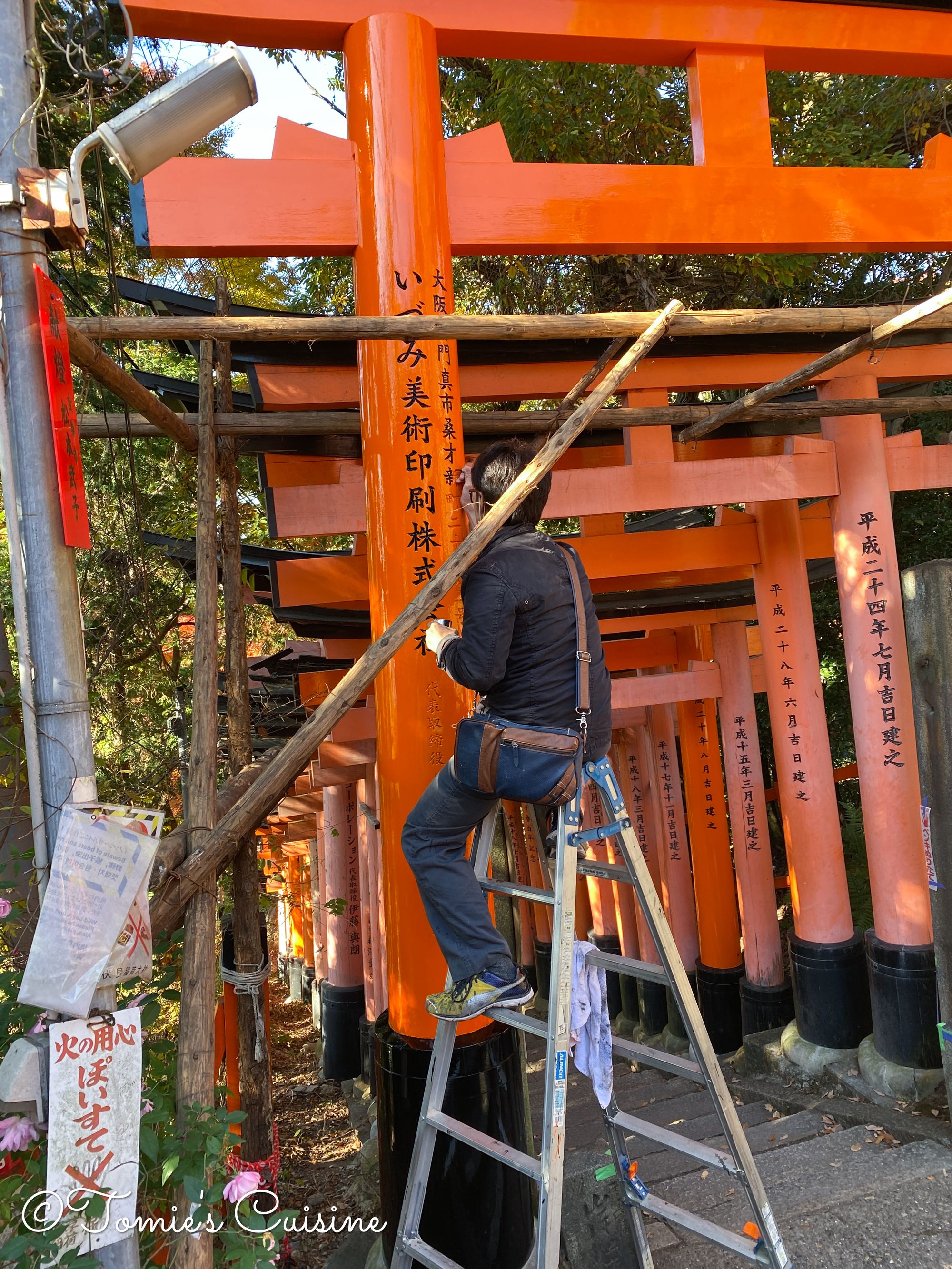 A painter writing the name of a donator on a Torii gate